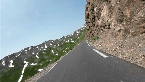 Smalle bergweg langs rotswand met sneeuwvelden in de Alpen